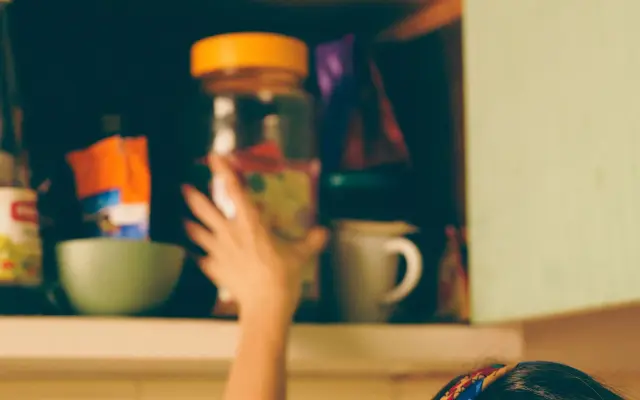 Woman reaching into crowded cupboard